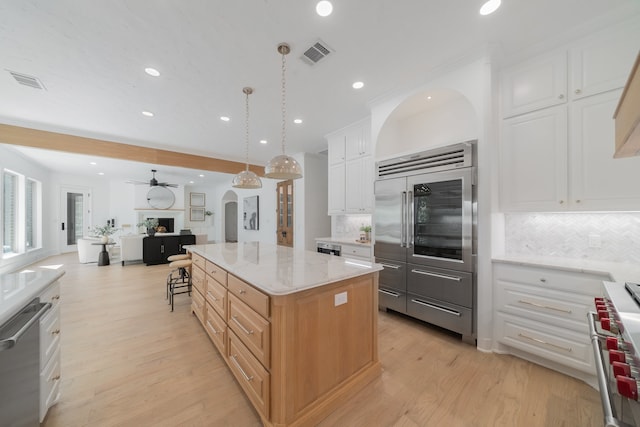 kitchen featuring ceiling fan, white cabinetry, light wood-type flooring, high quality appliances, and a center island