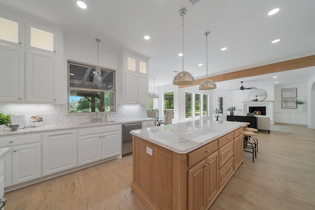 kitchen featuring tasteful backsplash, a center island, decorative light fixtures, stainless steel dishwasher, and white cabinets