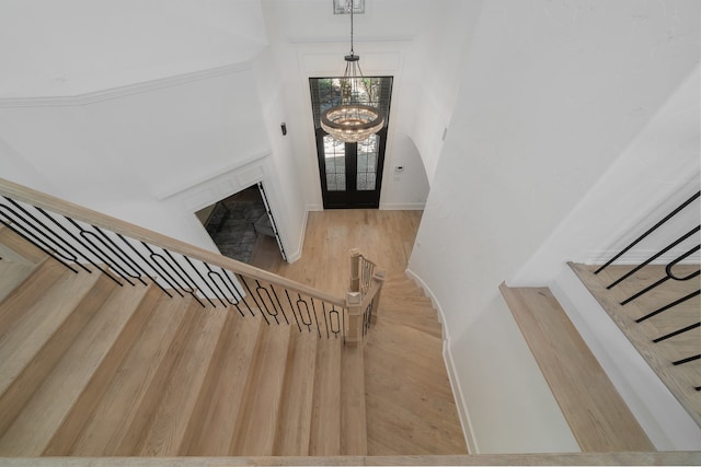 entryway featuring french doors, light hardwood / wood-style flooring, and an inviting chandelier