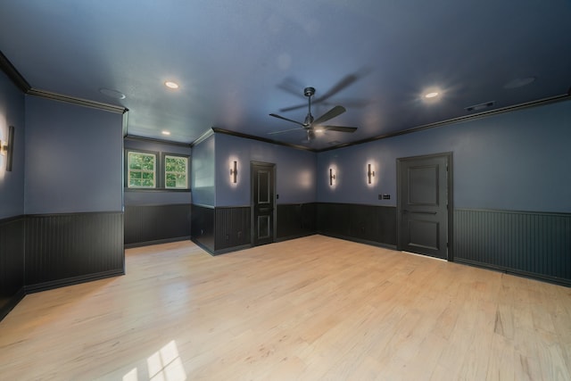 empty room featuring ceiling fan, ornamental molding, light hardwood / wood-style flooring, and wooden walls