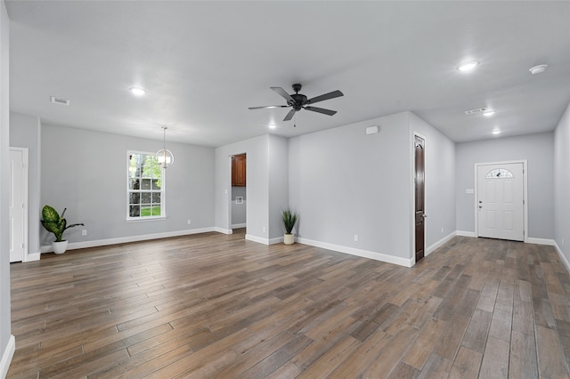 unfurnished living room with dark hardwood / wood-style flooring and ceiling fan with notable chandelier