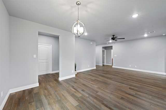 empty room with ceiling fan with notable chandelier and dark hardwood / wood-style floors