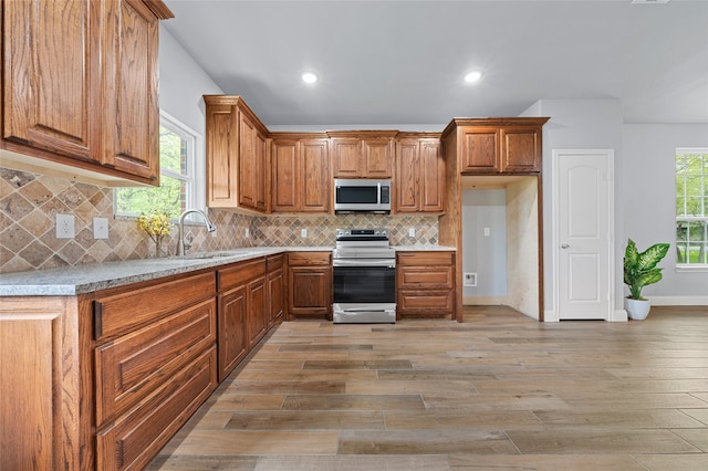 kitchen with appliances with stainless steel finishes, hardwood / wood-style floors, sink, and backsplash