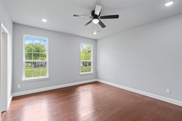 spare room featuring dark wood-type flooring, ceiling fan, and a wealth of natural light