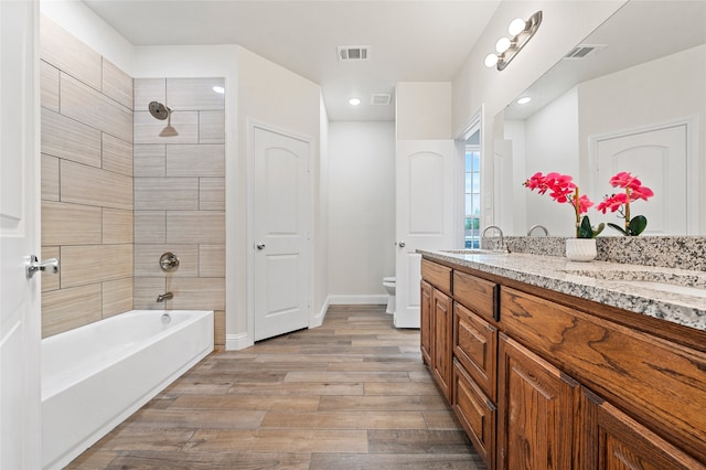 full bathroom featuring vanity, toilet, tiled shower / bath combo, and wood-type flooring