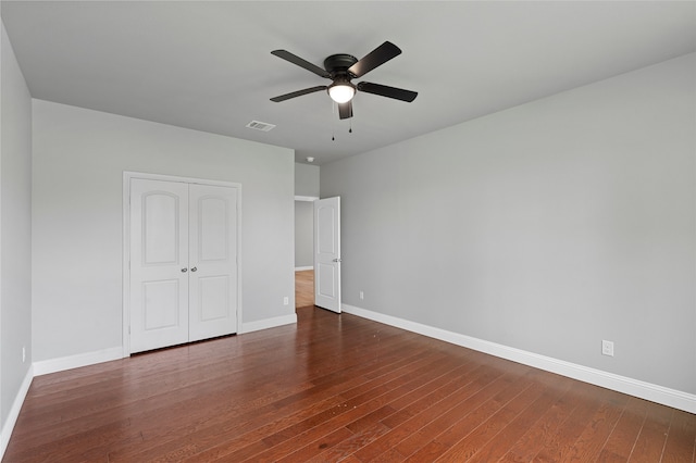 unfurnished bedroom with dark hardwood / wood-style floors, a closet, and ceiling fan