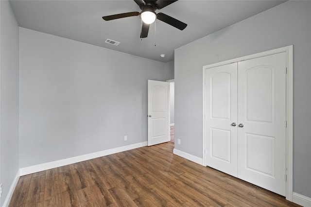 unfurnished bedroom with ceiling fan, a closet, and dark hardwood / wood-style flooring