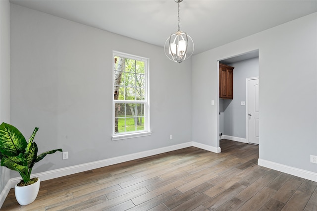 unfurnished room featuring a chandelier and hardwood / wood-style flooring