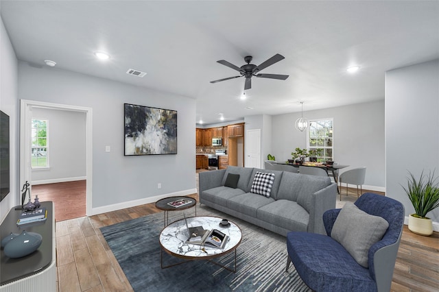 living room with wood-type flooring and ceiling fan with notable chandelier