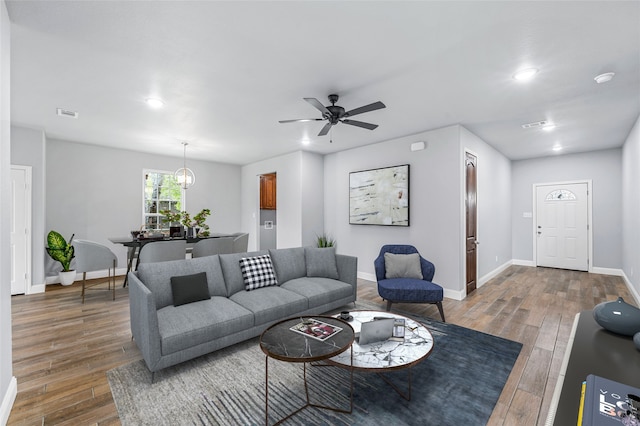 living room with ceiling fan with notable chandelier and dark hardwood / wood-style flooring