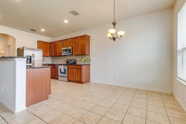 kitchen with tasteful backsplash, light tile floors, stainless steel appliances, a notable chandelier, and hanging light fixtures