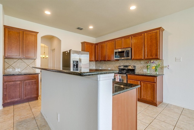 kitchen with backsplash, hanging light fixtures, stainless steel appliances, and light tile flooring