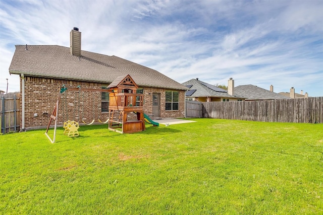 back of property with a lawn and a playground