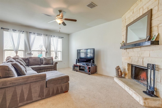 living room with light colored carpet, a stone fireplace, and ceiling fan