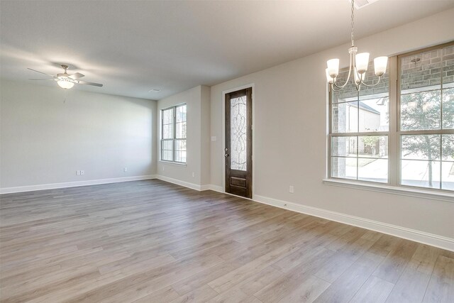 unfurnished living room featuring ceiling fan with notable chandelier and light hardwood / wood-style floors