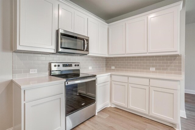 kitchen with stainless steel appliances, white cabinetry, tasteful backsplash, and light wood-type flooring