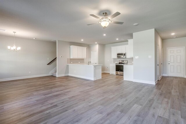 interior space featuring ceiling fan with notable chandelier and light hardwood / wood-style flooring