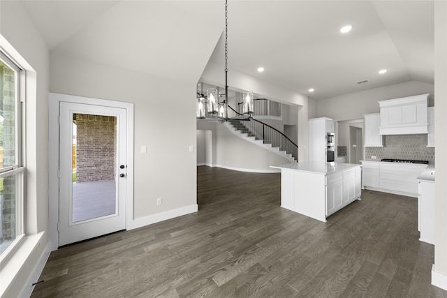 kitchen with lofted ceiling, backsplash, decorative light fixtures, dark hardwood / wood-style flooring, and white cabinetry