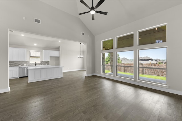 unfurnished living room with ceiling fan with notable chandelier, dark hardwood / wood-style flooring, and high vaulted ceiling