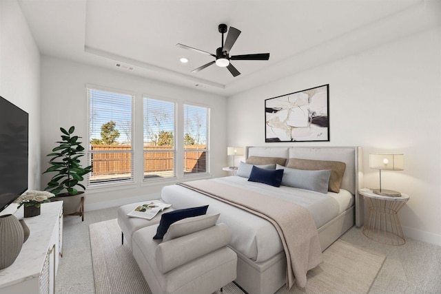 carpeted bedroom with a raised ceiling and ceiling fan