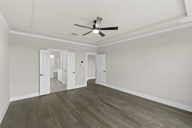 unfurnished bedroom featuring connected bathroom, a tray ceiling, ceiling fan, and dark wood-type flooring