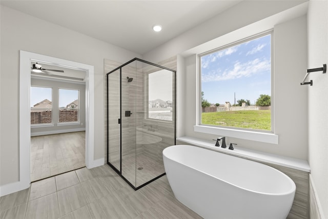 bathroom featuring ceiling fan, a healthy amount of sunlight, and shower with separate bathtub