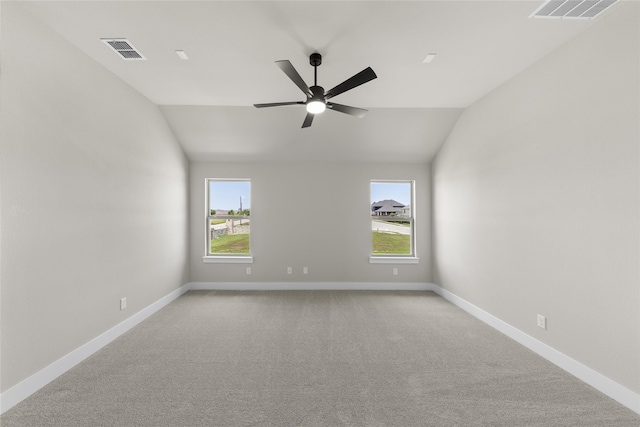 carpeted spare room featuring vaulted ceiling and ceiling fan