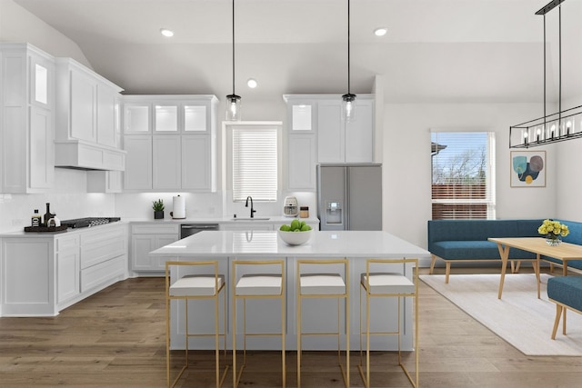 kitchen featuring white cabinets, a center island, stainless steel appliances, and sink