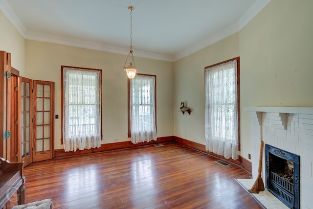 unfurnished living room featuring crown molding, dark hardwood / wood-style flooring, a fireplace, and a wealth of natural light