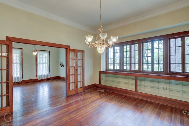 spare room with crown molding, dark hardwood / wood-style flooring, and a notable chandelier