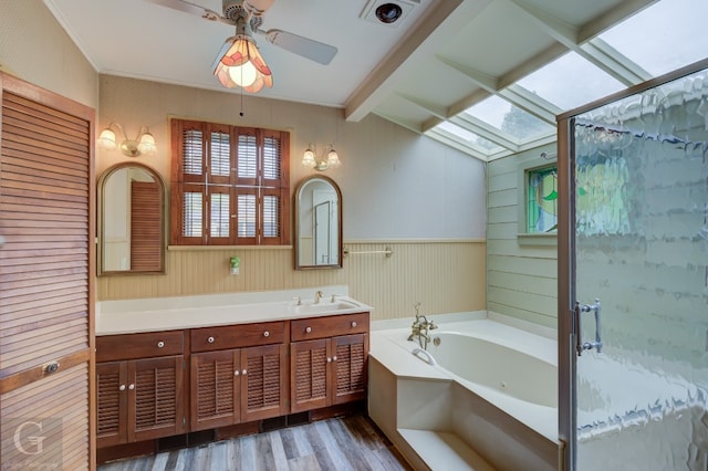 bathroom with vaulted ceiling with skylight, ceiling fan, hardwood / wood-style floors, vanity, and a bathtub