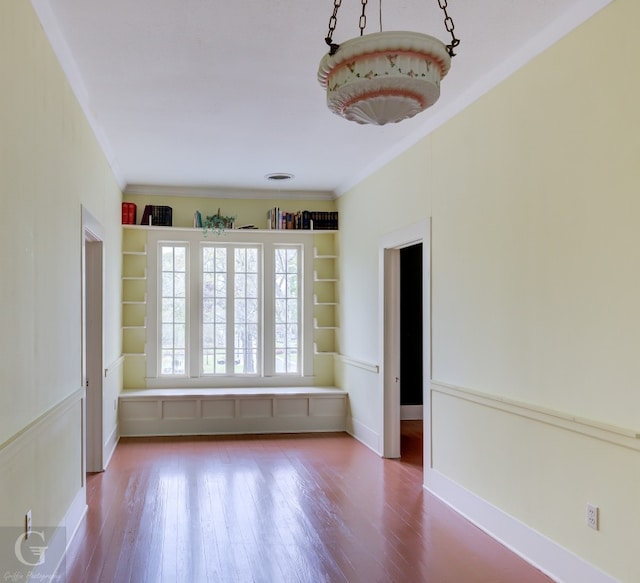 unfurnished room featuring built in features, ornamental molding, and wood-type flooring