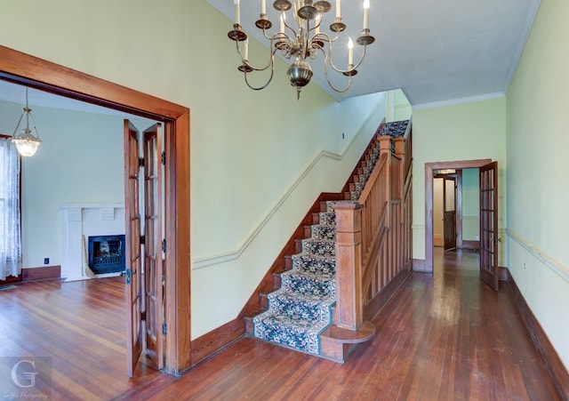 stairway featuring crown molding, french doors, dark hardwood / wood-style flooring, and a chandelier