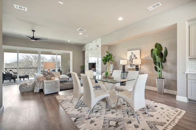 dining room featuring dark hardwood / wood-style floors, a fireplace, and ceiling fan