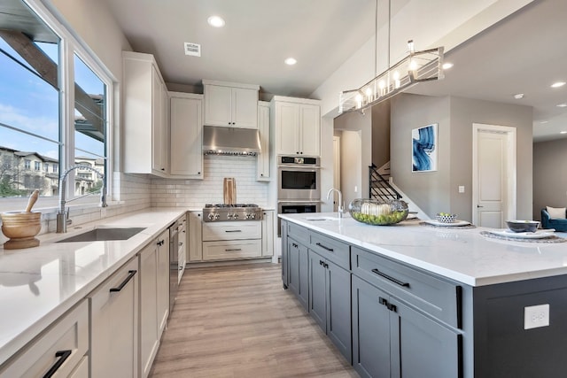 kitchen with light wood-type flooring, pendant lighting, white cabinetry, and light stone counters