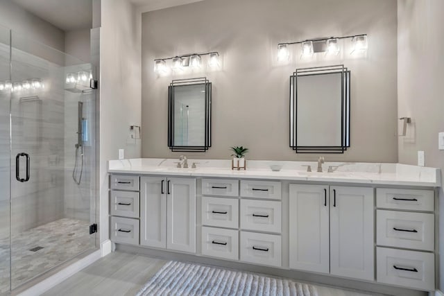 bathroom featuring dual sinks, a shower with door, and vanity with extensive cabinet space