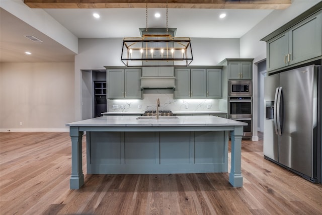 kitchen featuring appliances with stainless steel finishes, wood-type flooring, beamed ceiling, and a kitchen island with sink