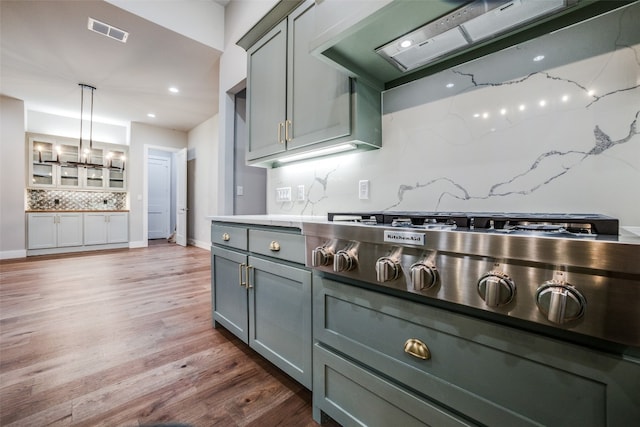 kitchen featuring hanging light fixtures, hardwood / wood-style floors, tasteful backsplash, and custom range hood