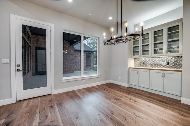 unfurnished dining area featuring a notable chandelier and light wood-type flooring