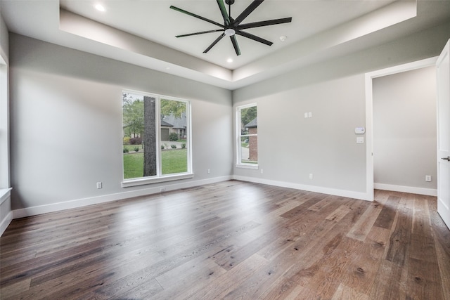 unfurnished room featuring wood-type flooring, ceiling fan, and a raised ceiling