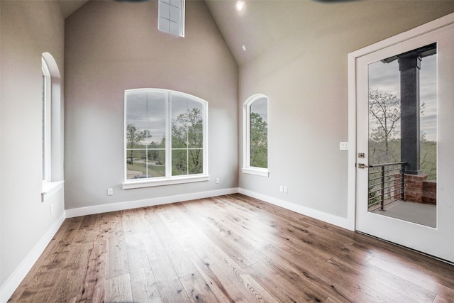 empty room featuring wood-type flooring and high vaulted ceiling