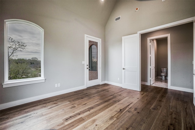 empty room with high vaulted ceiling and hardwood / wood-style flooring