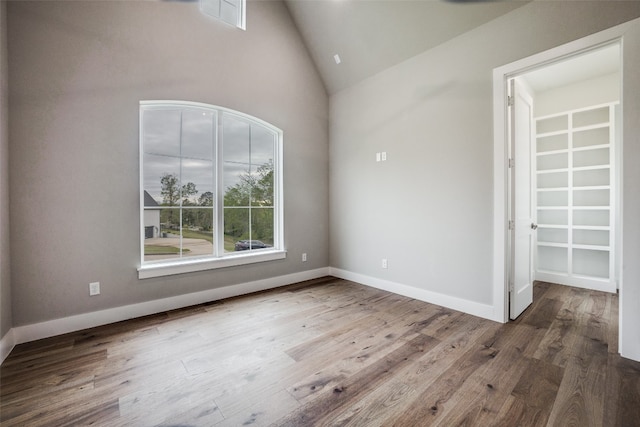 unfurnished room with hardwood / wood-style flooring and high vaulted ceiling