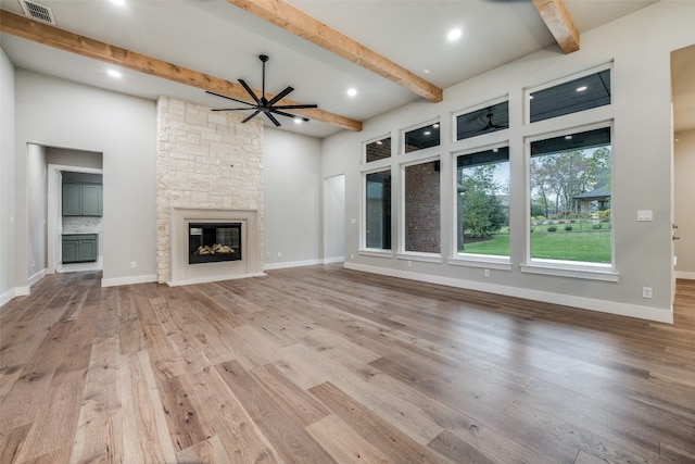 unfurnished living room featuring wood-type flooring, beam ceiling, and a fireplace