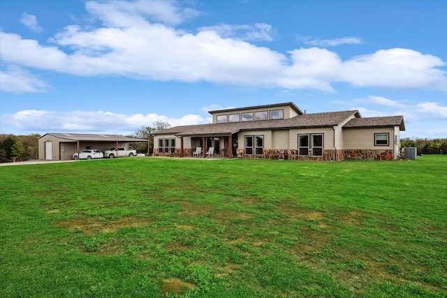 back of property featuring a lawn, central air condition unit, and a garage