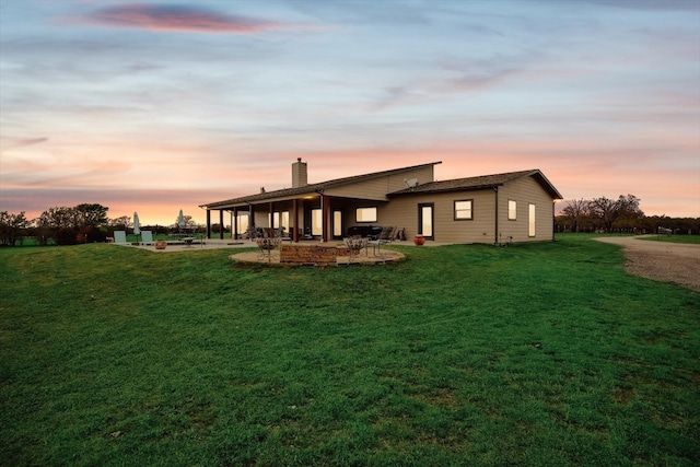 back house at dusk featuring a yard and a patio area