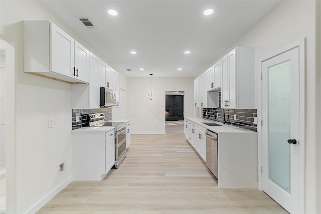 kitchen with backsplash, stainless steel appliances, white cabinetry, and sink