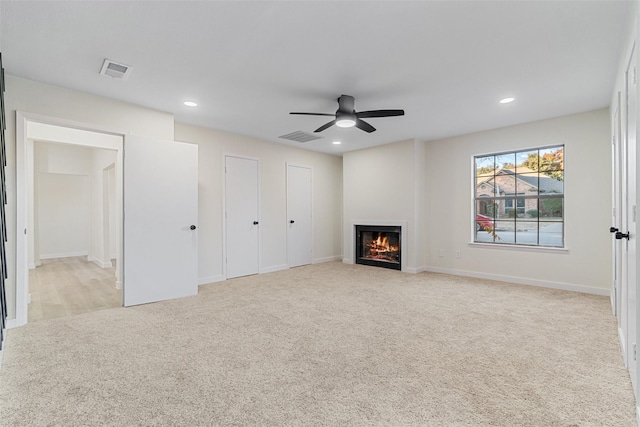 unfurnished living room featuring ceiling fan and light carpet