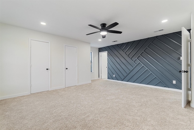 unfurnished bedroom with carpet, ceiling fan, and two closets