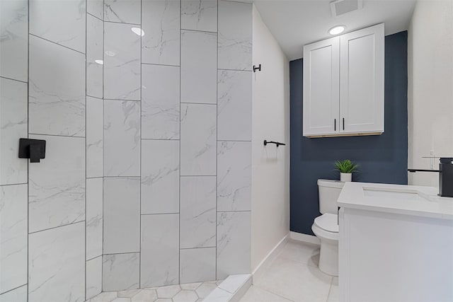 bathroom with tile patterned flooring, vanity, toilet, and tiled shower